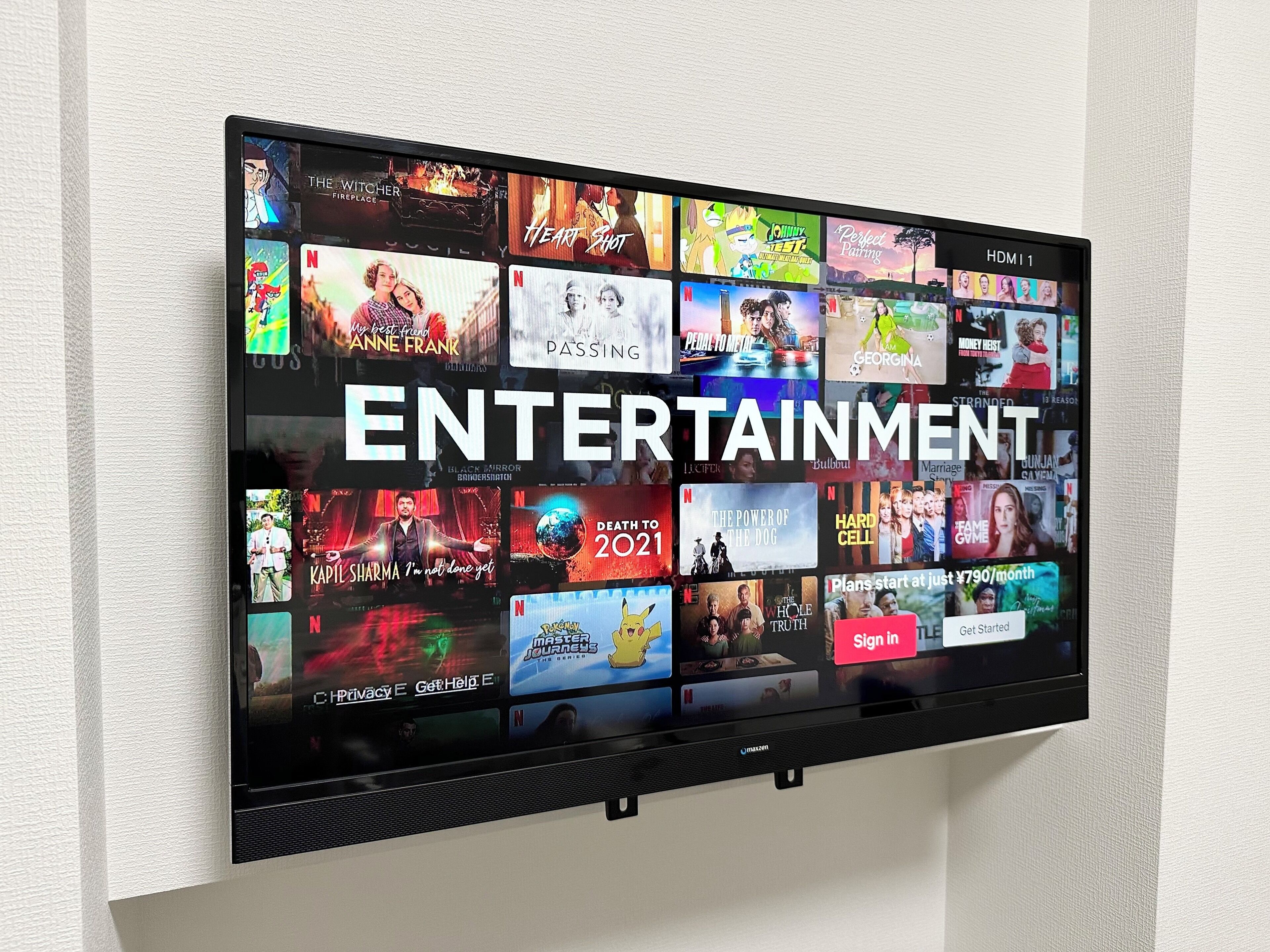 A flat-screen TV mounted on a wall displaying a variety of entertainment options including movies and TV shows.