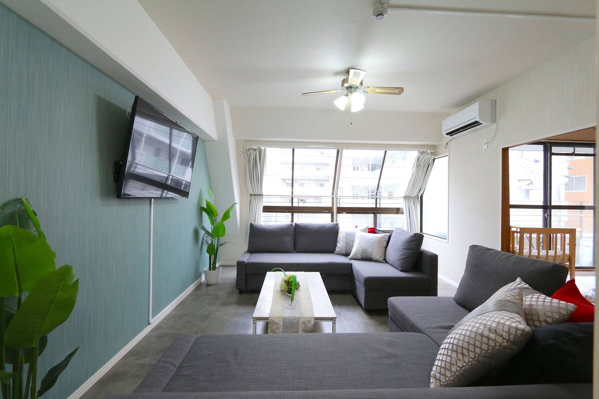 A modern living room with a grey sofa, a white coffee table, and a ceiling fan.