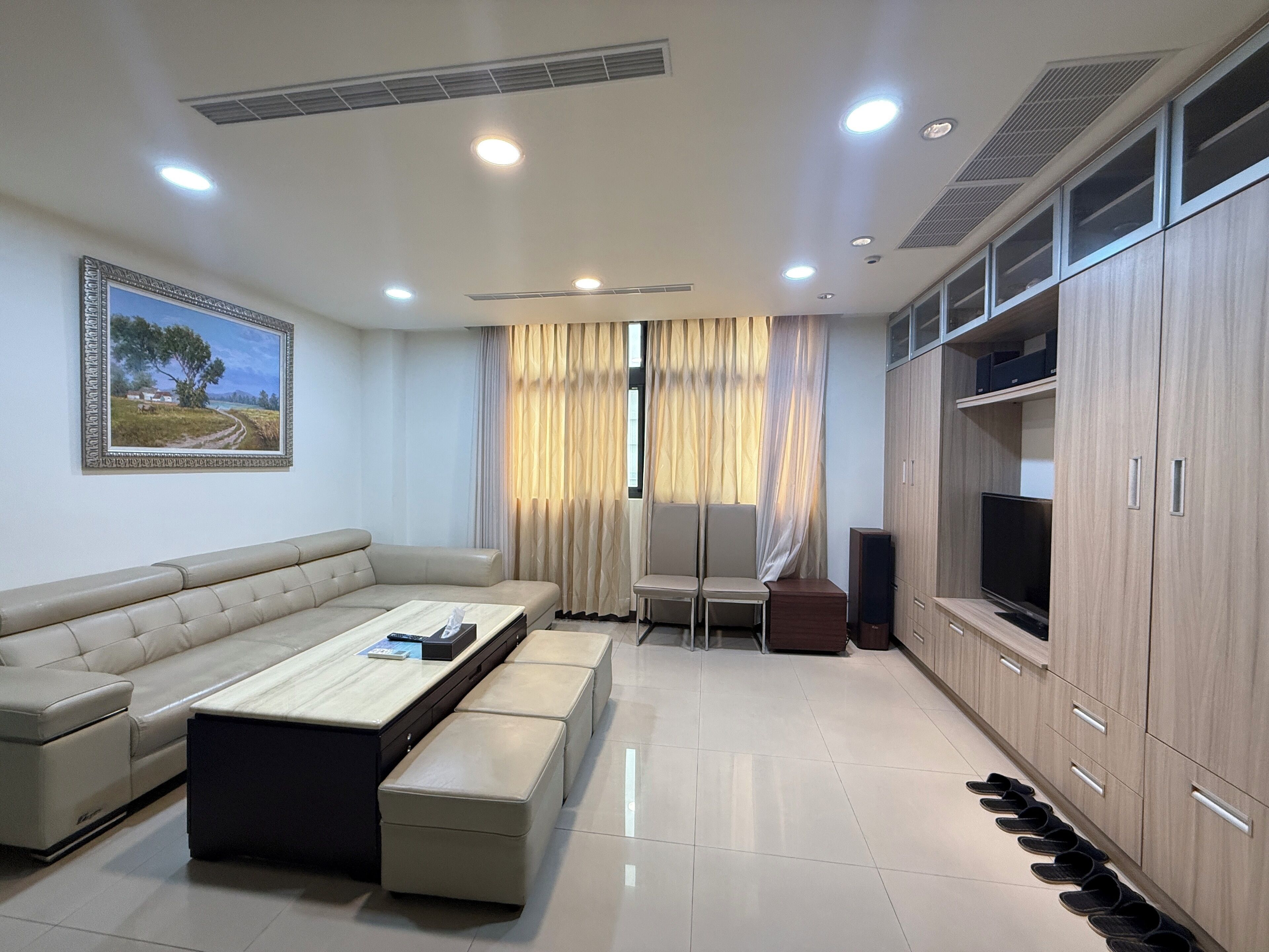 Una sala de estar moderna con sofá, mesa de centro, televisor y aparador.