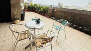 A rooftop terrace with a tiled floor, a round table with chairs, and potted plants. - Frank's Hostel (Jincheng)