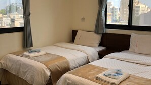 A hotel room with two beds, a window with curtains, and a view of buildings outside. - Frank's Hostel (Jincheng)