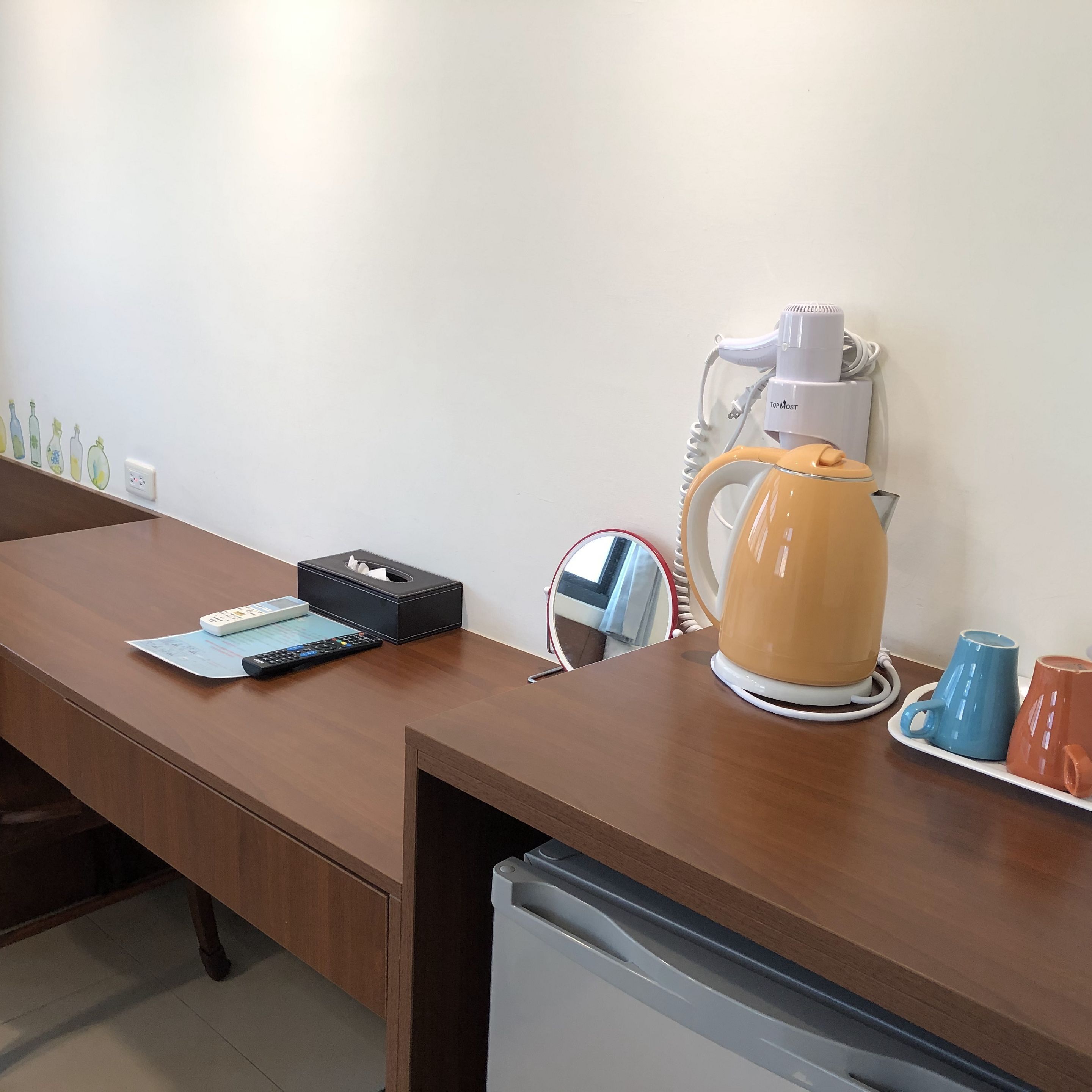 A wooden desk with a tissue box, remote control, and a mug.
