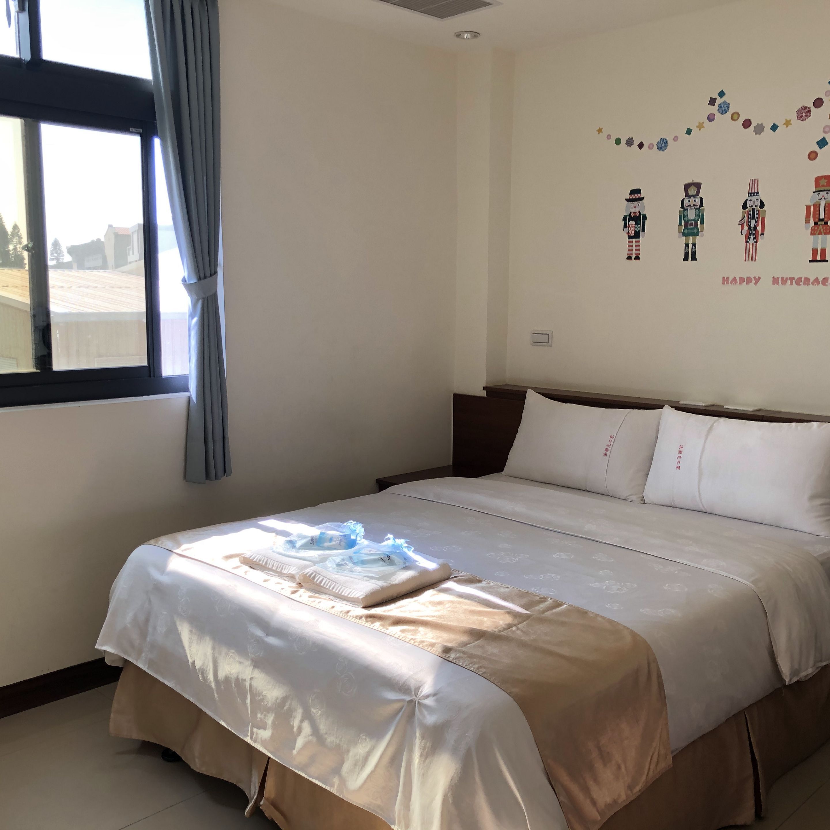 Habitación de hotel con una cama grande, una ventana con cortinas y una decoración de pared con figuras de cascanueces.