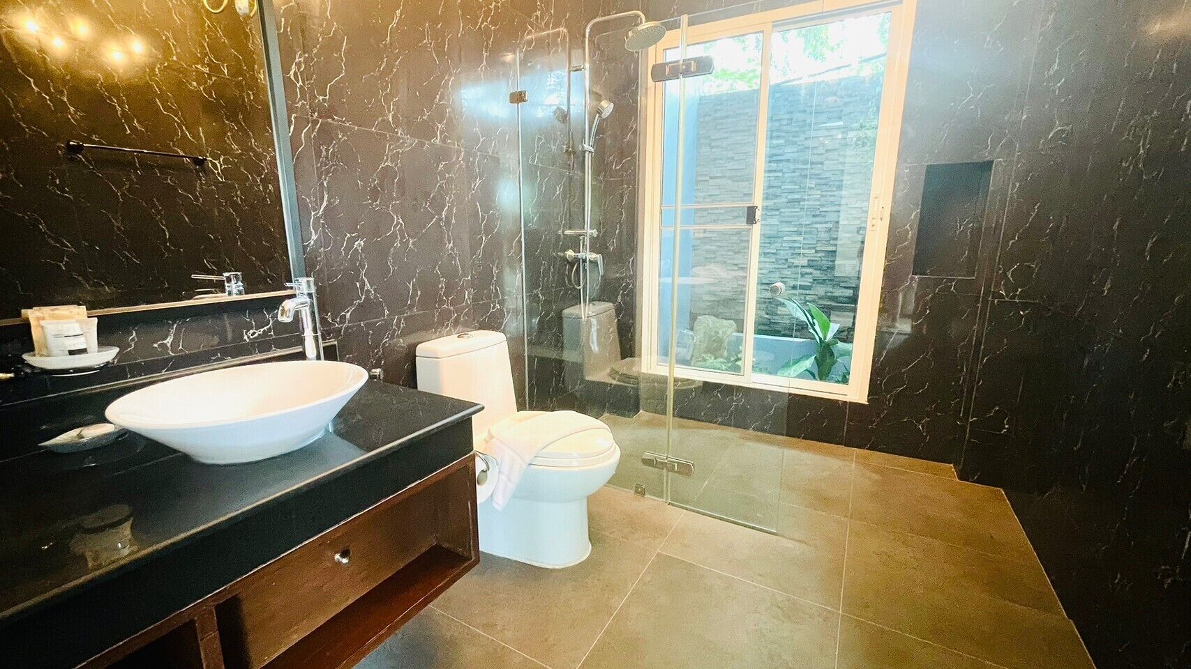 Une salle de bain moderne avec un grand lavabo blanc, des toilettes et une douche à parois de verre.