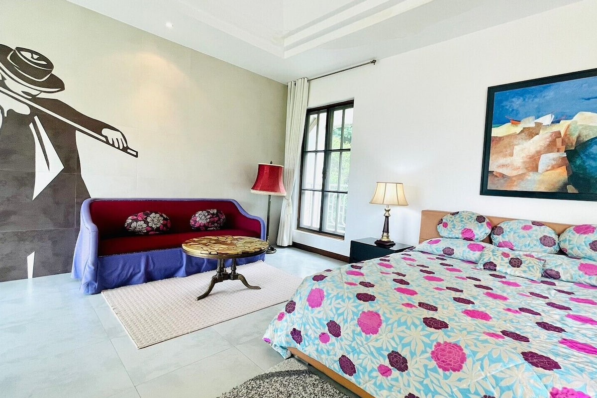 Une chambre à coucher avec un lit, un canapé, une table et un tableau au mur.