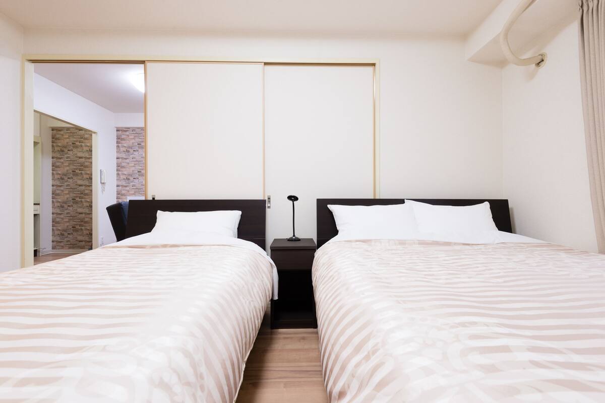 Una habitación de hotel con dos camas, una pared de ladrillo y una puerta corredera.