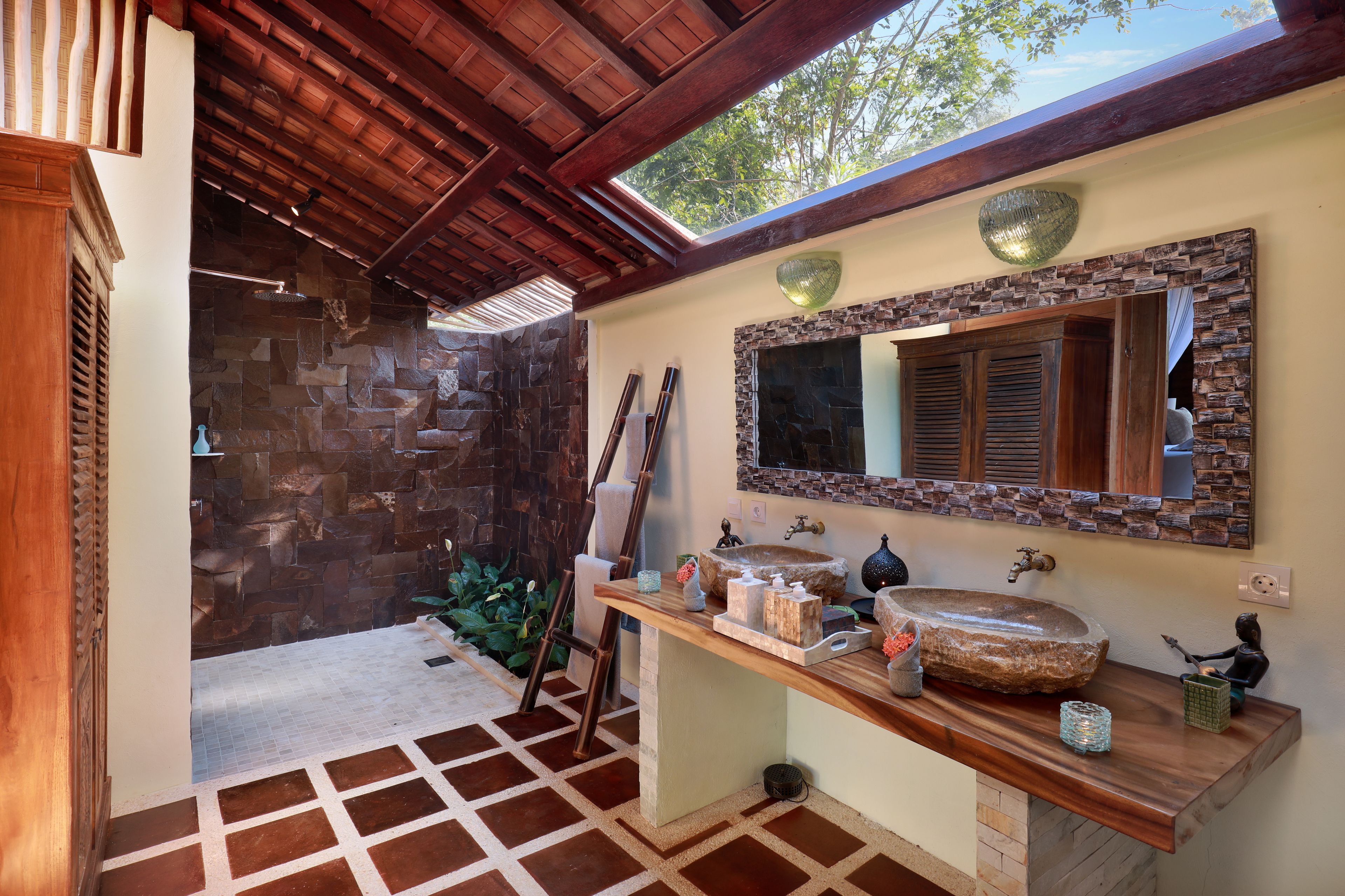 A bathroom with a stone wall, wooden ceiling, and a large mirror.