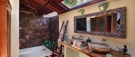 A bathroom with a stone wall, wooden ceiling, and a large mirror.