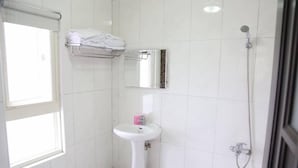 A small, clean bathroom with a white sink, a mirror, a towel rack, and a shower. - Sunflower B&B (Hualien City)