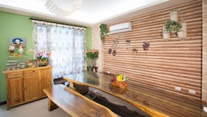 A dining area with a wooden table and bench, a green wall, and decorative items including a plant and a small statue. - Sunflower B&B (Hualien City)