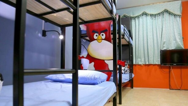 A bunk bed room with a large Angry Birds mural on the wall, a television, and a window with curtains. - Sunflower B&B (Hualien City)