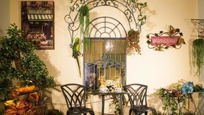 A cozy indoor garden with a wrought iron gate, two chairs, a small table with a floral arrangement, and various potted plants. - Sunflower B&B (Hualien City)