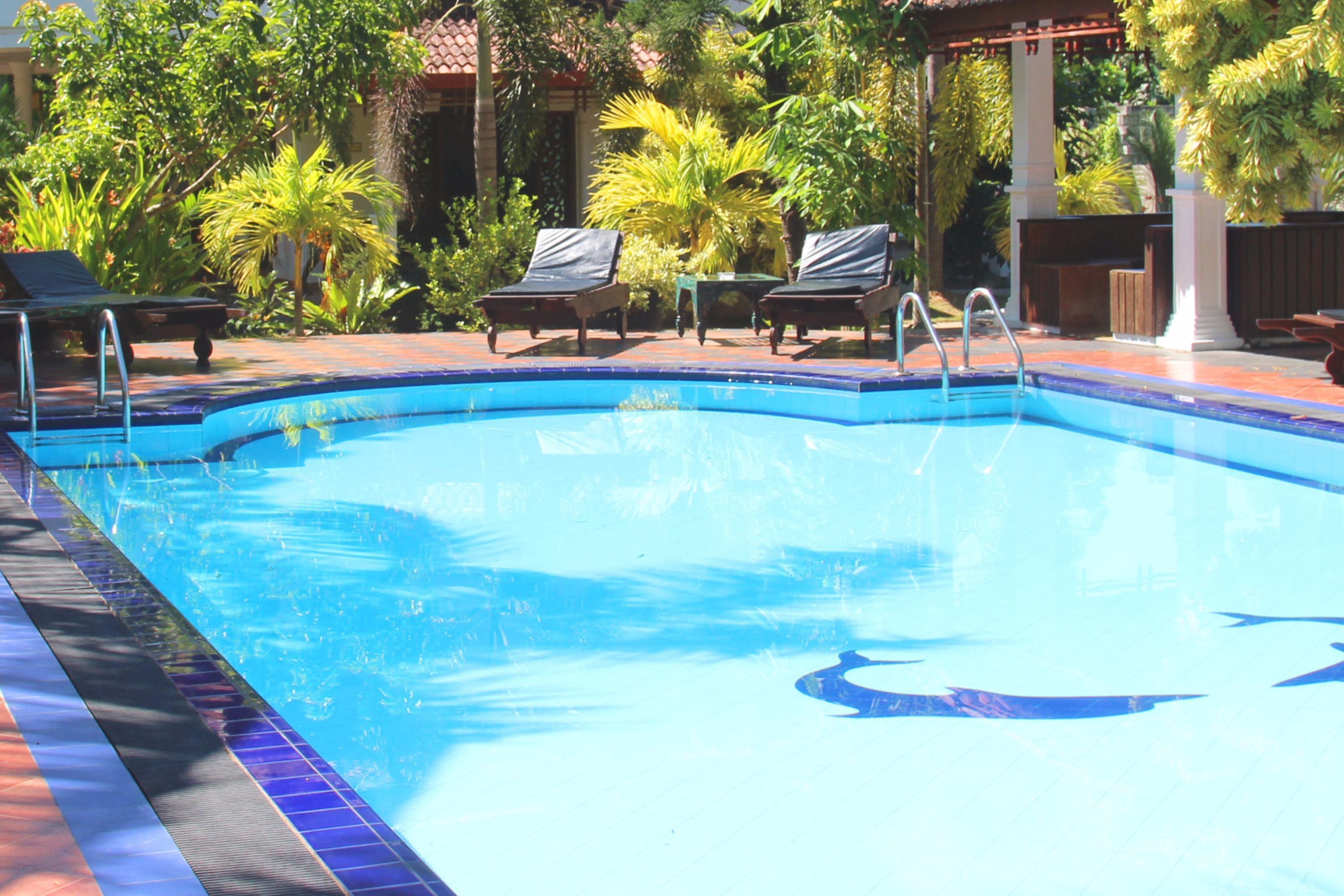 A swimming pool with lounge chairs and a pergola.