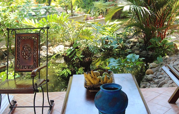 A garden view with a table, chair, and a basket of fruit.