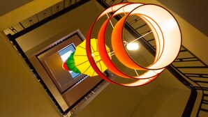 Una escalera de caracol con diseño moderno, que presenta una pared amarilla y una barandilla negra.