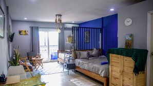 Un dormitorio moderno con cama, armario de madera, mesita de vidrio y balcón con vistas.