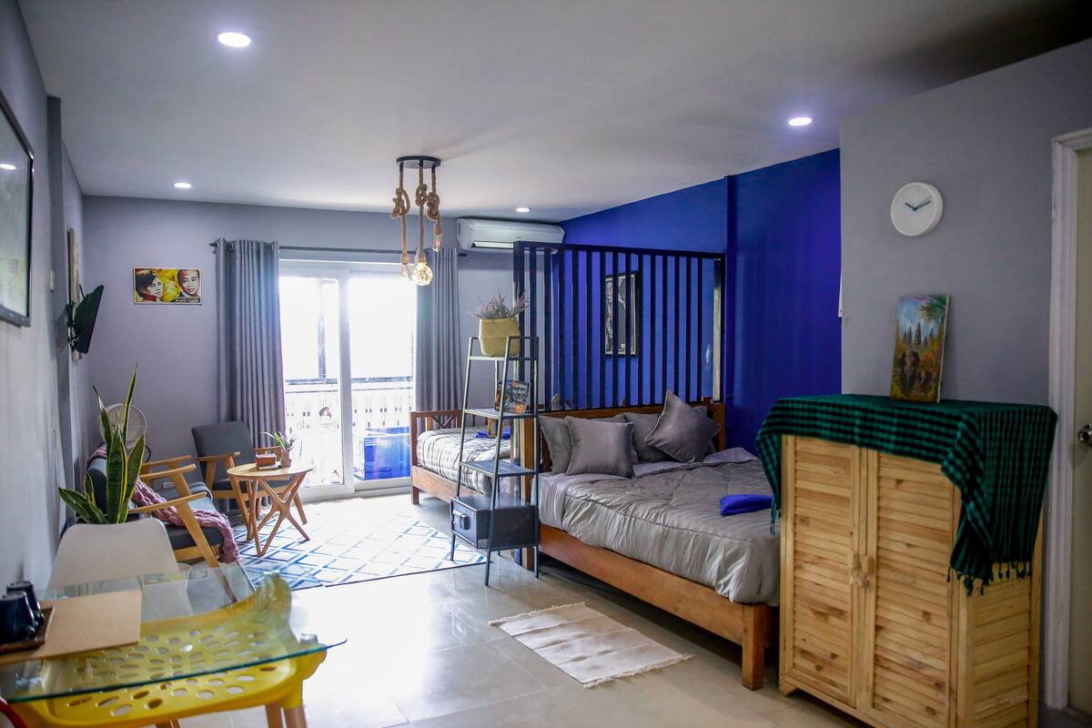 Ein modernes Schlafzimmer mit einem Bett, einem Holzschrank, einem Glastisch und einem Balkon mit Aussicht.