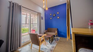 Una habitación con una pared azul de acento, una mesa de madera con sillas, una alfombra estampada y vistas a un área exterior a través de una puerta de cristal.