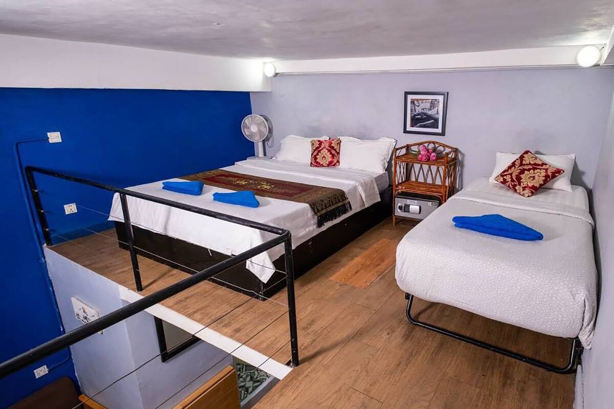 Ein Schlafsaalzimmer mit zwei Betten, Holzboden und blauer Wand.
