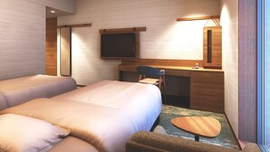 Ein Hotelzimmer mit zwei Betten, einem Schreibtisch mit Stuhl, einem Flachbildfernseher und einem kleinen runden Tisch.