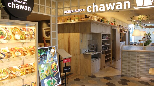 Ein Restaurantinneres mit einer Auswahl an Gerichten, Holzvertäfelung und einem Schild mit der Aufschrift 'Chawan'.