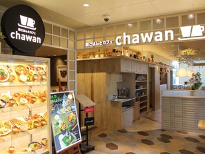 Interior de un restaurante con exhibición de varios platos, paneles de madera y un letrero que dice 'Chawan'.