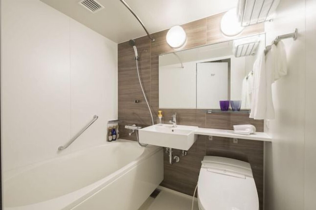 A modern bathroom with a bathtub, a toilet, a sink, and a mirror.