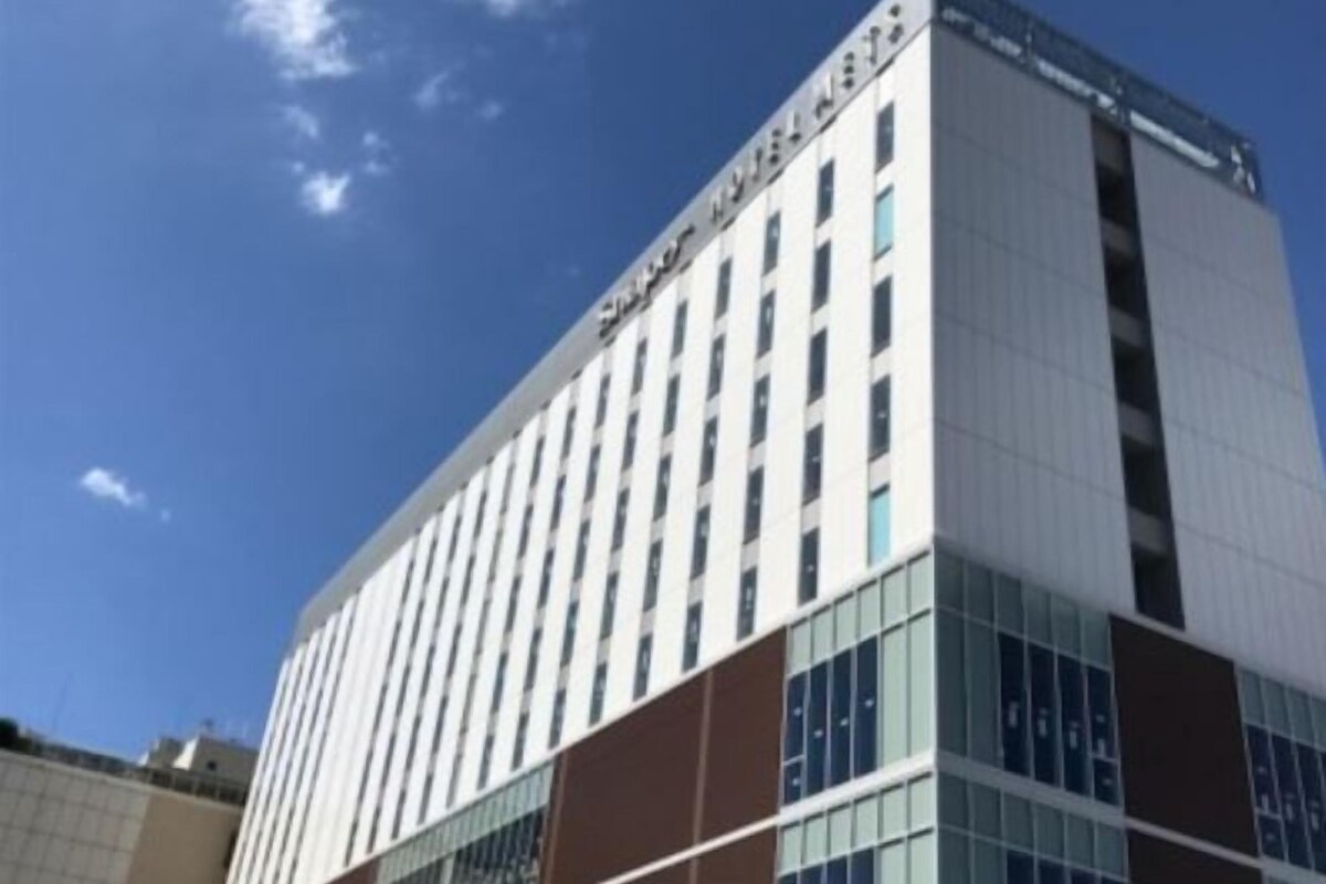 A multi-story hotel building with a modern architectural design, featuring a prominent entrance and a series of windows.