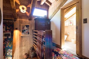 Un intérieur rustique avec des éléments en bois, un plafond en pente, un banc en bois, un tapis coloré et une petite fenêtre.