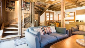 A rustic wooden interior with a staircase, a sofa, and a kitchen area.