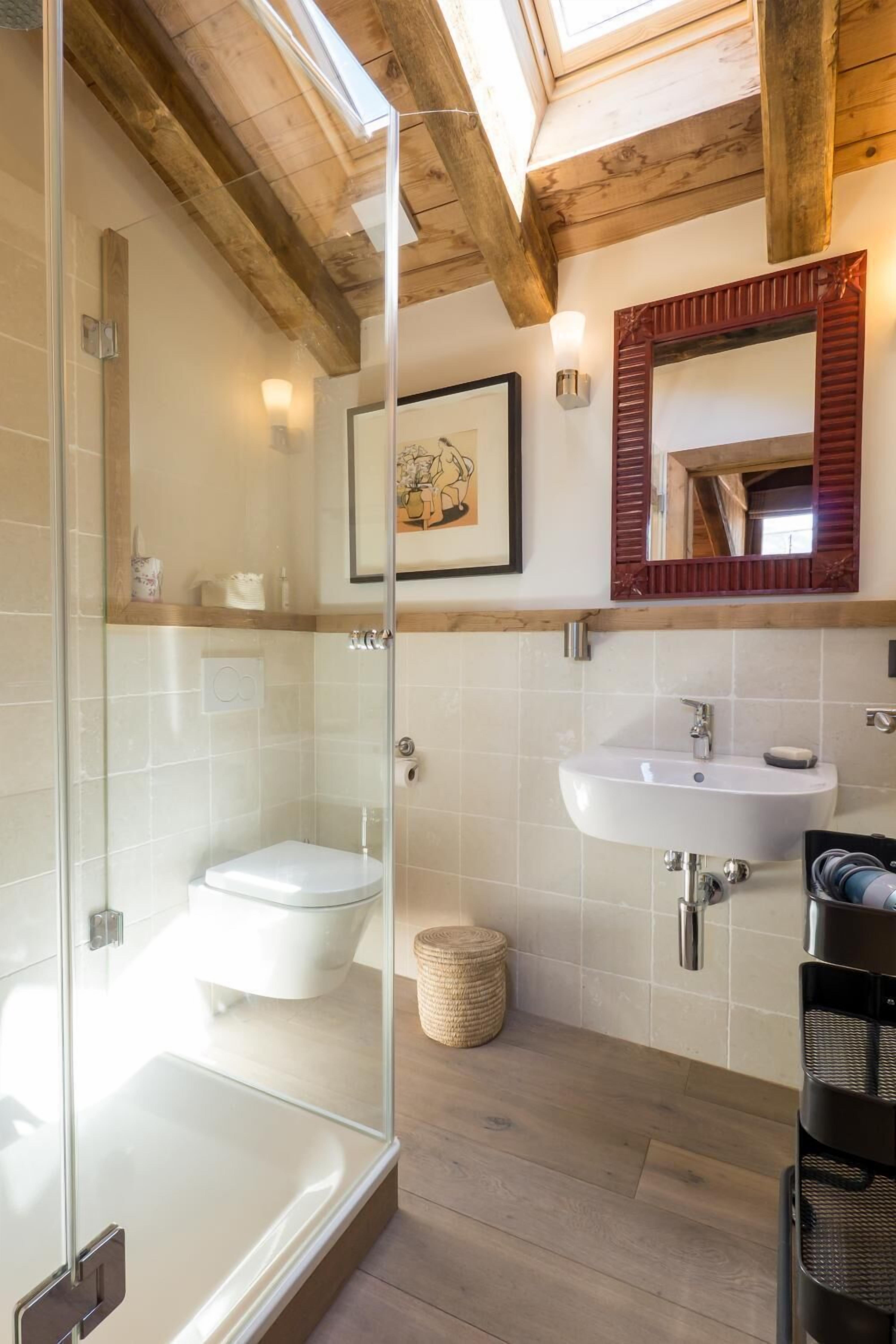 Ein modernes Badezimmer mit einer begehbaren Glasdusche, einer weißen Toilette und einem Waschbecken mit Spiegel darüber.