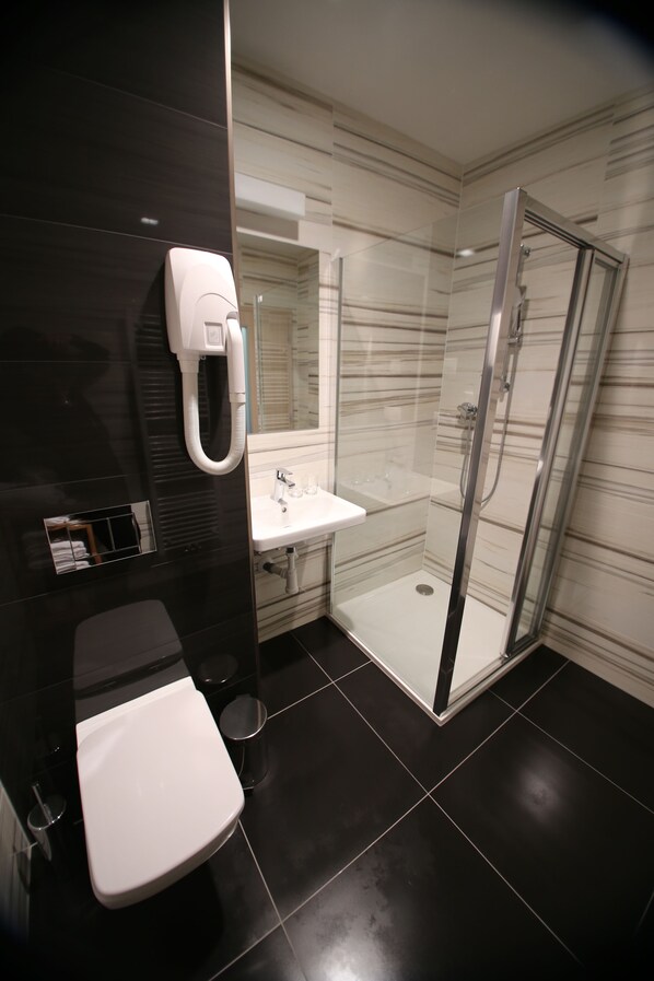 A modern bathroom with a toilet, sink, and glass-enclosed shower. - Wellness Penzion U Gigantu (Plzen)