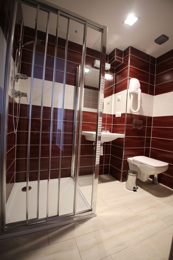 A modern bathroom with a glass-enclosed shower, a white sink, and a toilet. - Wellness Penzion U Gigantu (Plzen)