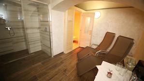 Ett hotellrum med dusch, två fåtöljer, ett bord med glas och en nyckelring samt en dörr som leder till ett badrum.
