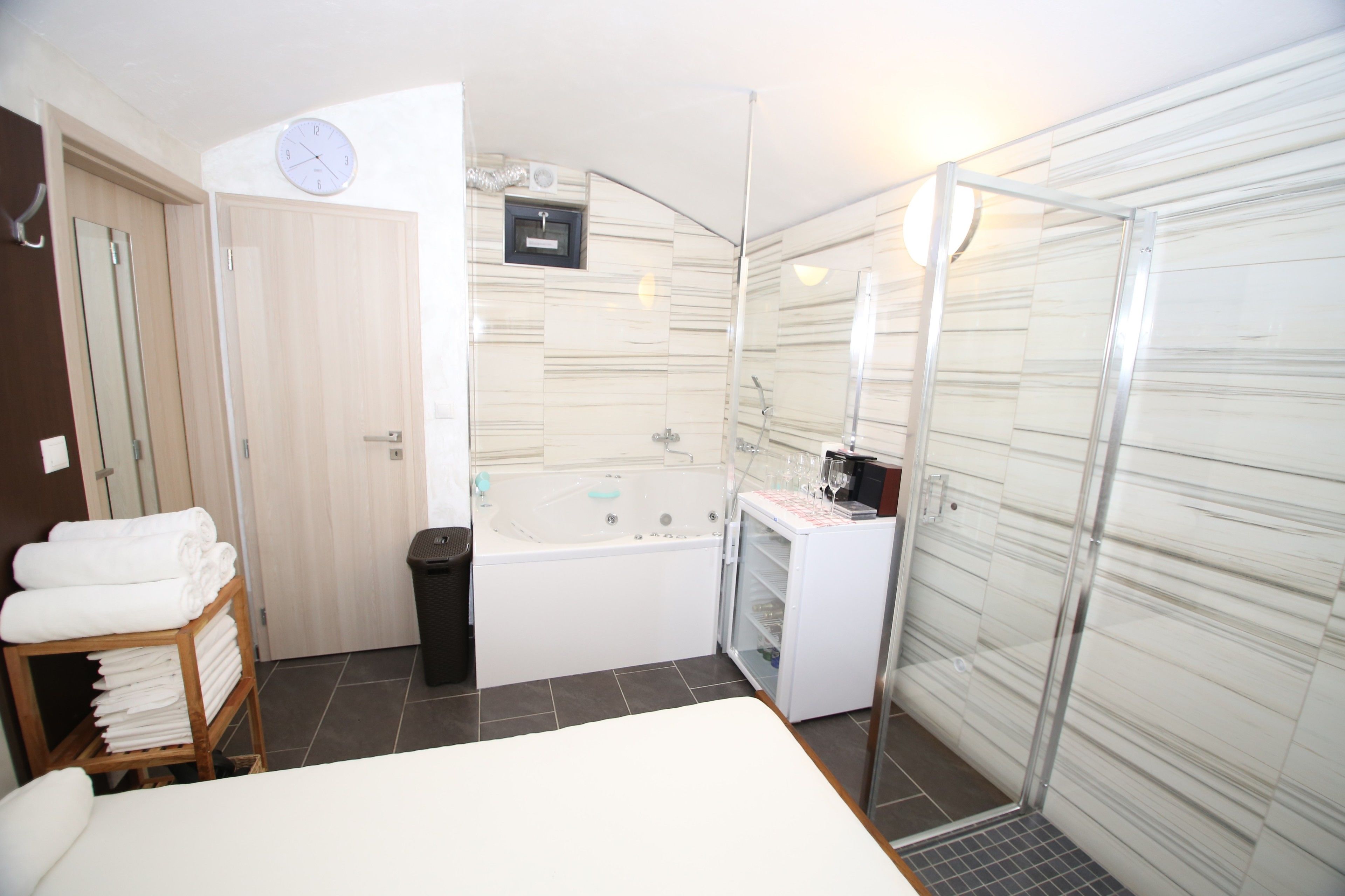 Un baño moderno con bañera, cabina de ducha de vidrio y un reloj en la pared.