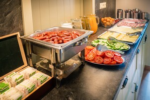 Un bufé con diferentes opciones de comida, incluyendo salchichas, tomates en rodajas y queso.