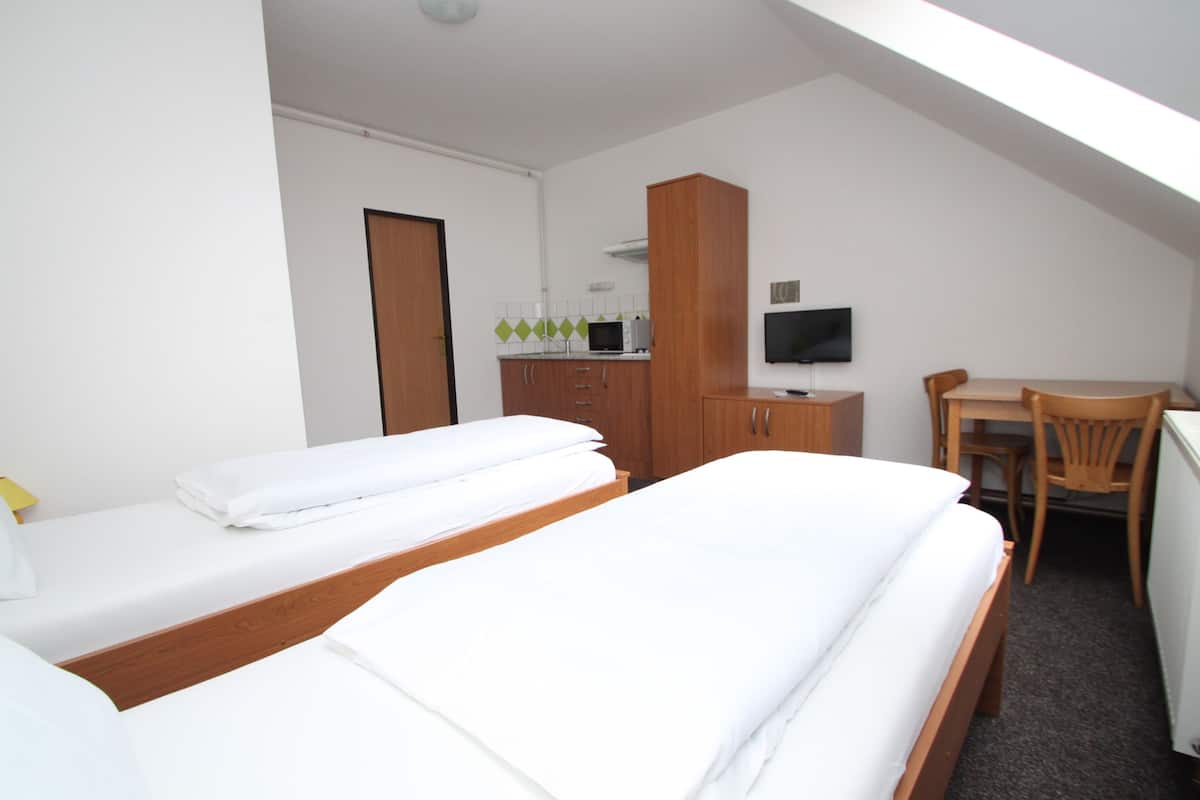 A hotel room with two beds, a desk, a chair, a television, and a cabinet.