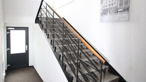 A staircase with a black railing and a wooden handrail, leading to a door with a frosted glass window. - Penzion U Gigantu (Plzen)