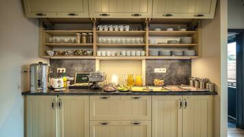 A kitchen with light-colored cabinets, a marble backsplash, and various kitchen appliances and utensils on the countertop.