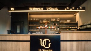 A bar area with shelves of bottles and glasses, a sign reading "U Gigantu," and a wooden counter. - Penzion U Gigantu (Plzen)