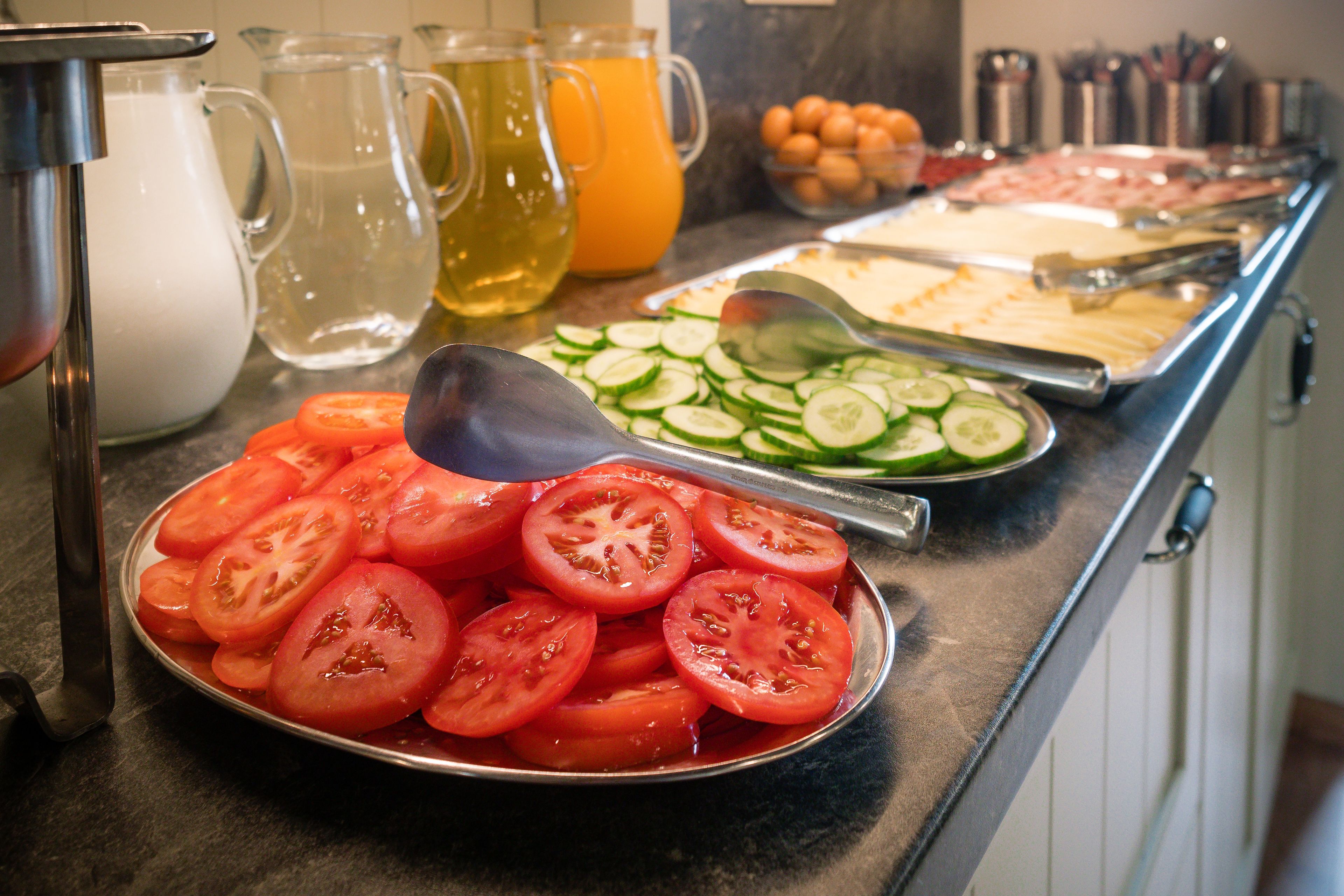 Un buffet proposant des tomates en tranches, des concombres et divers autres aliments.