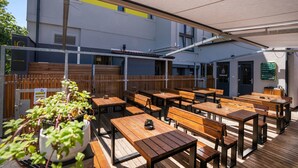 An outdoor seating area with wooden tables and benches, a potted plant, and a sign indicating a breakfast area. - Penzion U Gigantu (Plzen)
