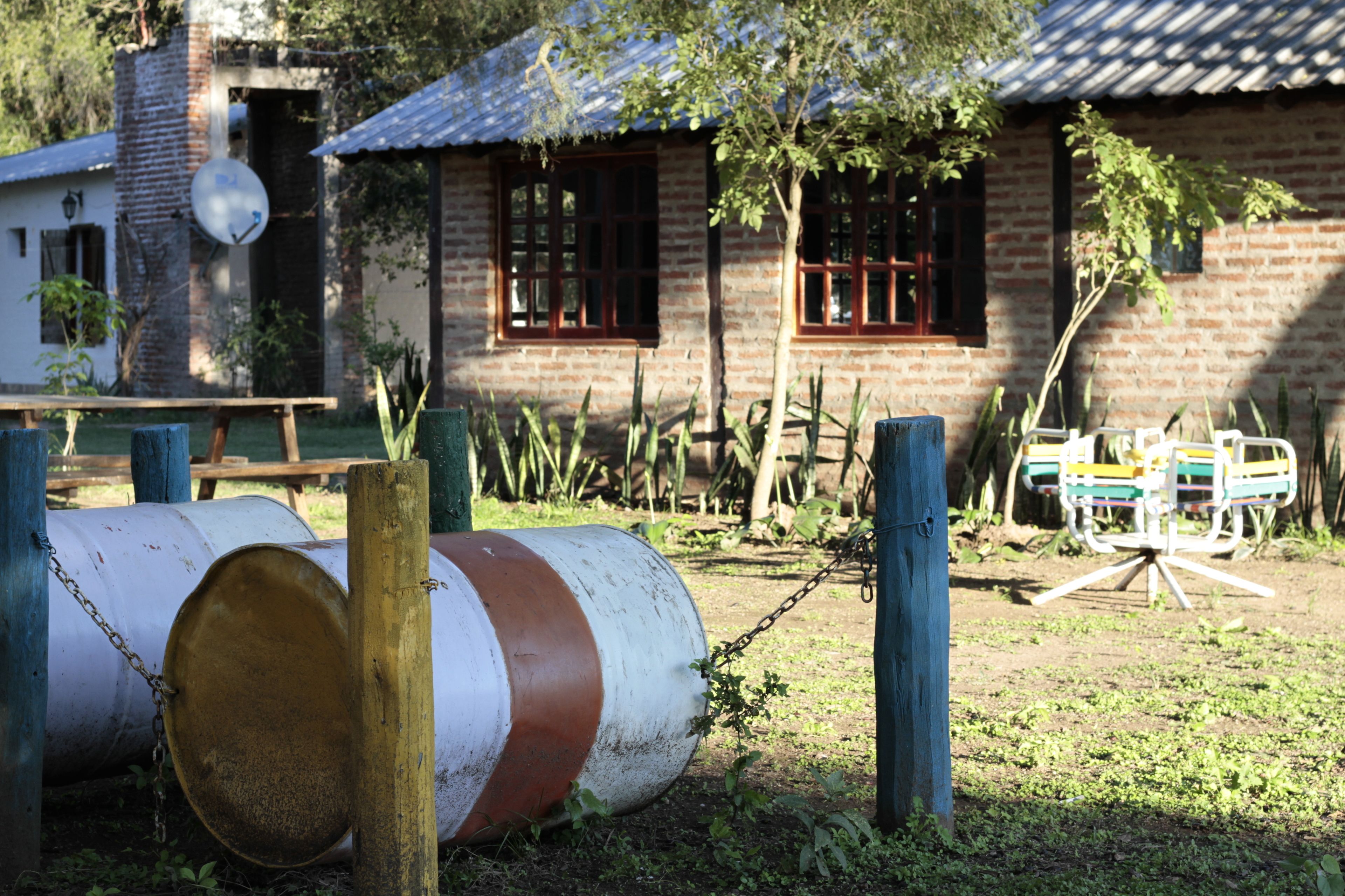 Una casa rústica con fachada de ladrillo, cerca de madera y un columpio en el jardín.