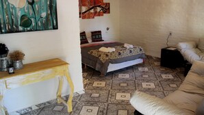 Ein Schlafzimmer mit einem Bett, einem Holztisch, einem dekorativen Gemälde und einem gemusterten Boden.