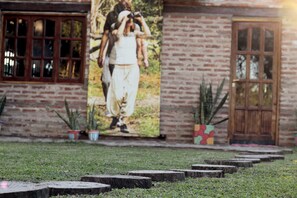 Un bâtiment en briques avec une grande affiche représentant un couple, des plantes en pot et une porte en bois.