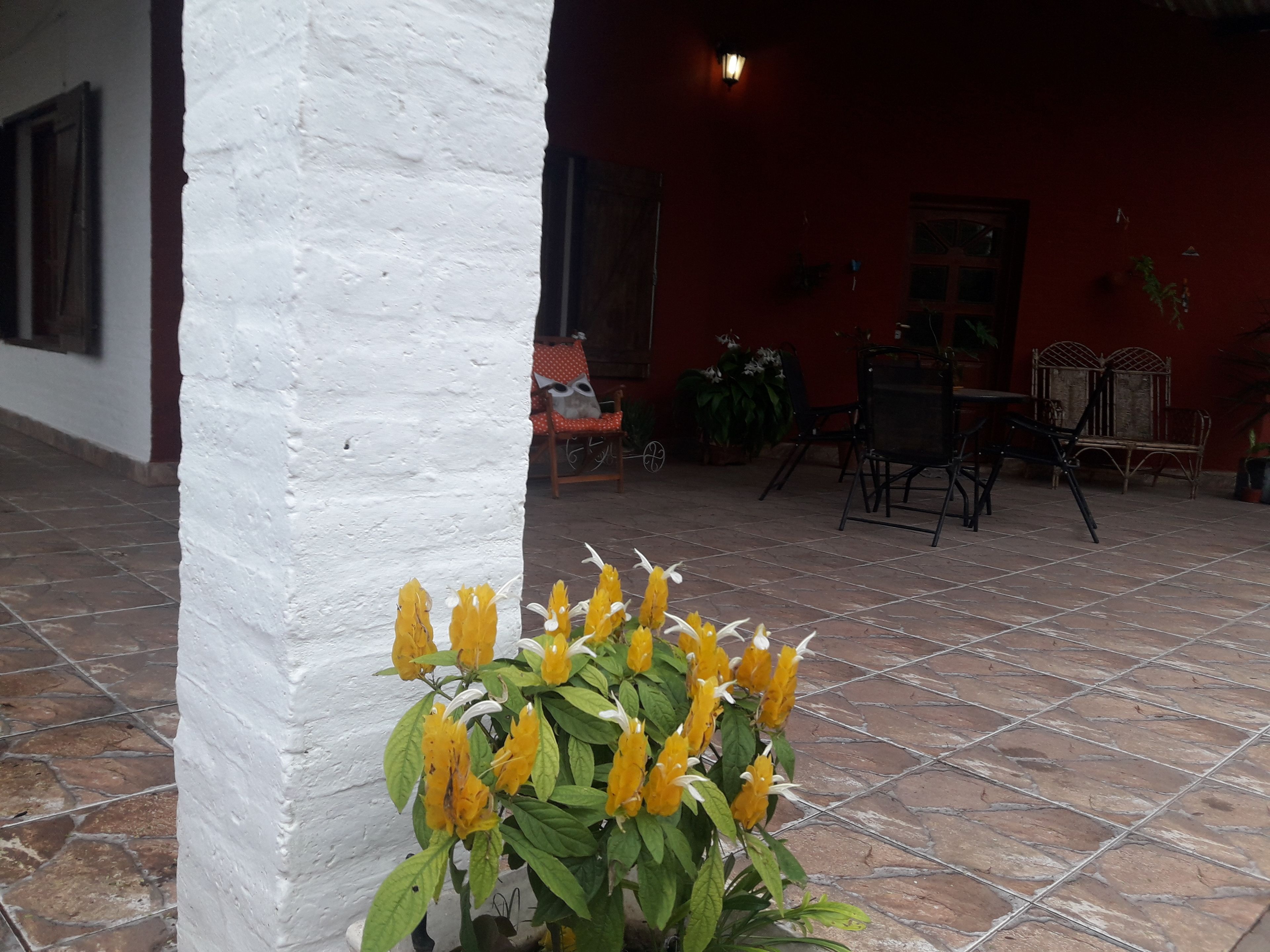 A patio area with a white wall, a tiled floor, and a table with chairs.