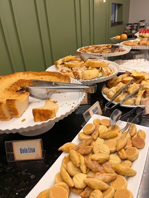 Un bufé con diversos platos, incluyendo una tarta, Bolo Liso y otras pastas.