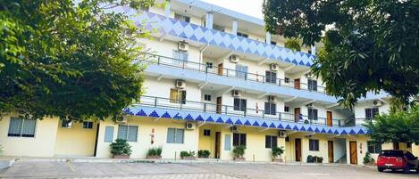 Un hotel de varios pisos con fachada de azulejos, balcones y un patio empedrado.