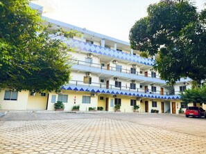 Un hotel de varios pisos con fachada de azulejos, balcones y un patio empedrado.