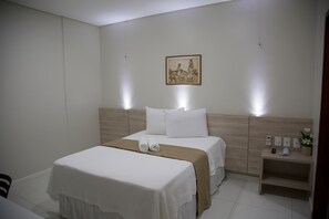 A hotel room with a bed, bedside tables, a nightstand, and a wall-mounted picture. - Hotel Padre Cícero (Juazeiro do Norte)